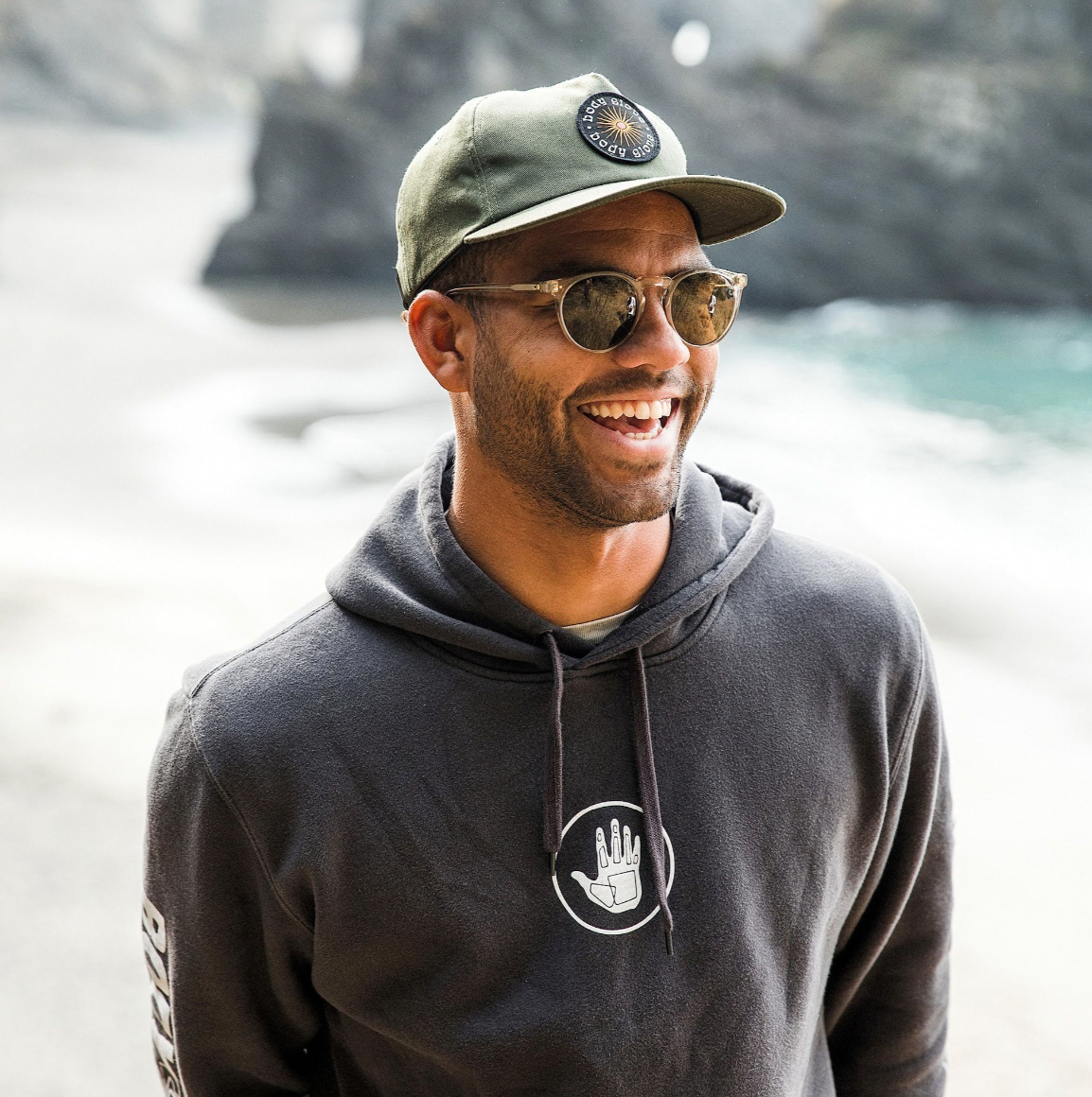 mean wearing sunglasses smiling in front of ocean